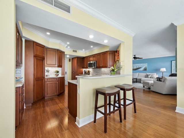 kitchen featuring hardwood / wood-style floors, ceiling fan, a kitchen bar, and tasteful backsplash