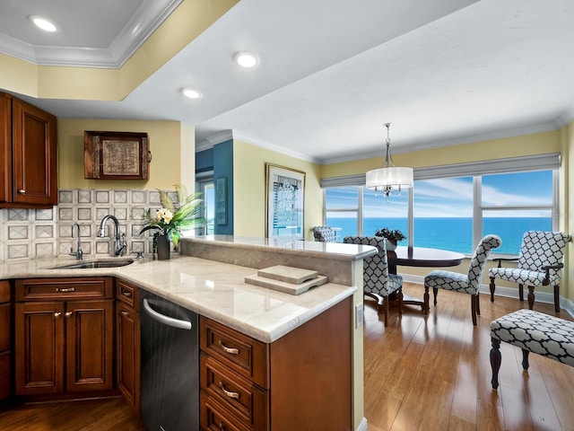 kitchen featuring decorative backsplash, sink, wood-type flooring, a water view, and hanging light fixtures