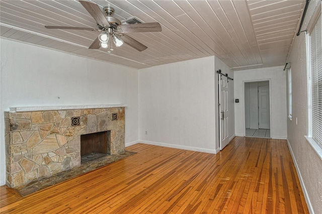 unfurnished living room with hardwood / wood-style flooring, wooden ceiling, a barn door, and a fireplace