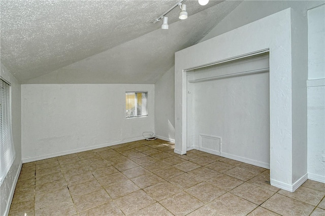 bonus room featuring light tile patterned flooring, a textured ceiling, and vaulted ceiling