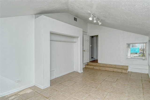 additional living space with a textured ceiling, light tile patterned floors, and lofted ceiling