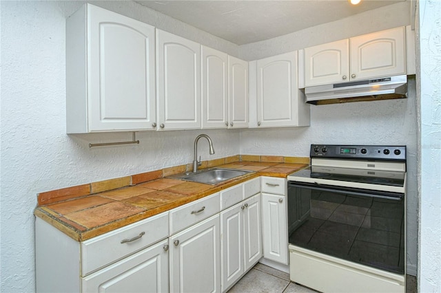 kitchen with light tile patterned floors, electric stove, white cabinets, and sink