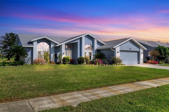 ranch-style home featuring a garage and a yard