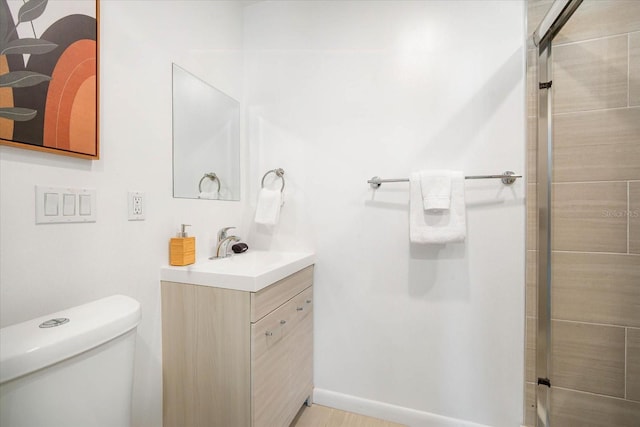 bathroom with toilet, vanity, and a shower with shower door