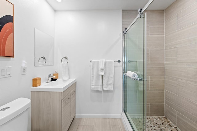 bathroom featuring toilet, a shower with door, and vanity