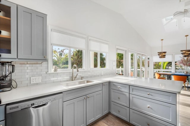 kitchen featuring sink, dishwasher, kitchen peninsula, gray cabinets, and lofted ceiling with skylight