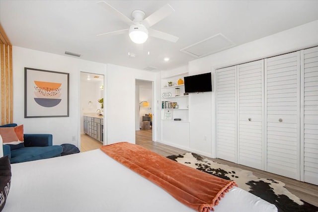 bedroom with ceiling fan, light wood-type flooring, ensuite bath, and sink