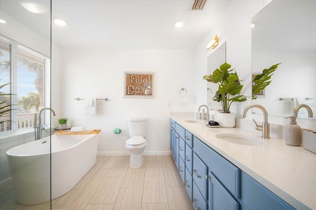 bathroom featuring toilet, a bathing tub, vanity, and plenty of natural light