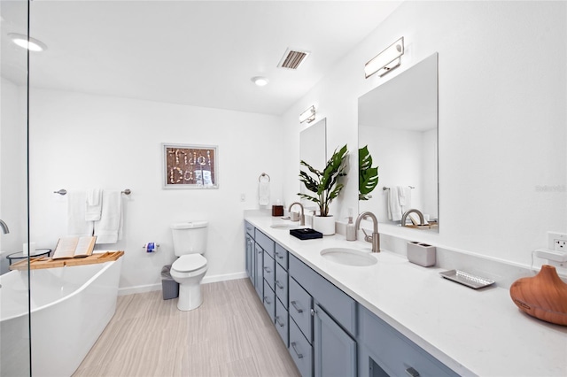 bathroom with toilet, a tub to relax in, and vanity