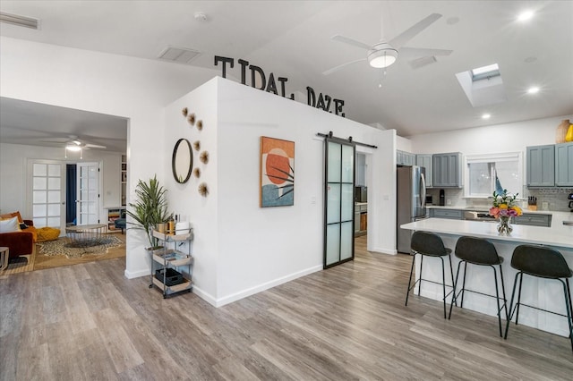 203 72nd St, Holmes Beach, FL 34217 - kitchen with light countertops, freestanding refrigerator, a ceiling fan, a kitchen breakfast bar, and light wood-style floors