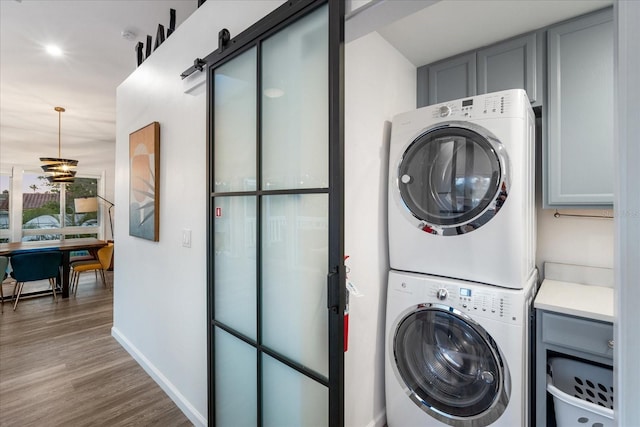 203 72nd St, Holmes Beach, FL 34217 - laundry room with stacked washer and dryer, wood finished floors, baseboards, and cabinet space