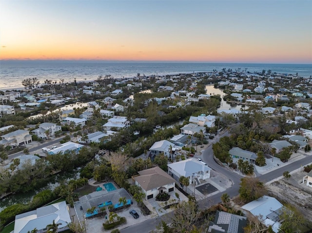 aerial view at dusk featuring a water view