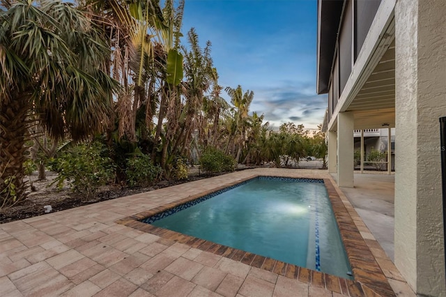 pool at dusk with a patio area