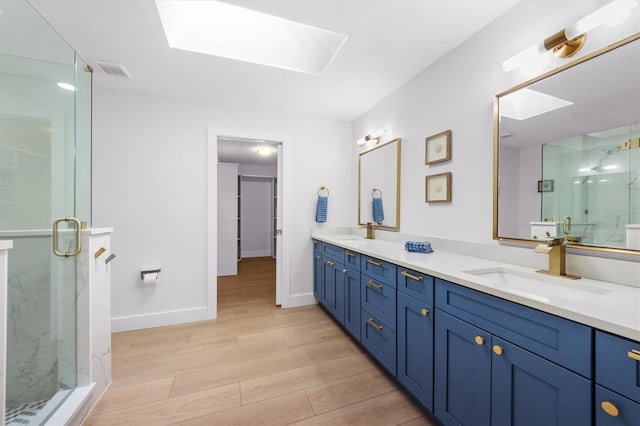 bathroom featuring a skylight, hardwood / wood-style floors, vanity, and walk in shower