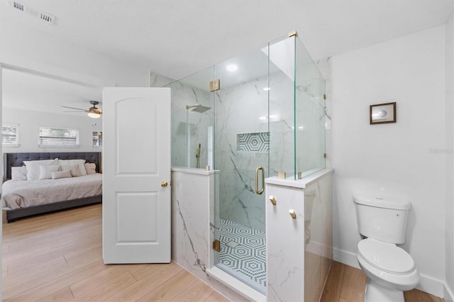 bathroom with hardwood / wood-style flooring, toilet, ceiling fan, and a shower with shower door