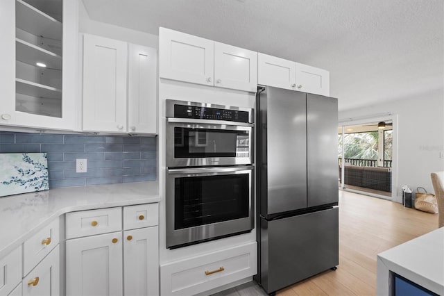 kitchen with appliances with stainless steel finishes, backsplash, and white cabinetry