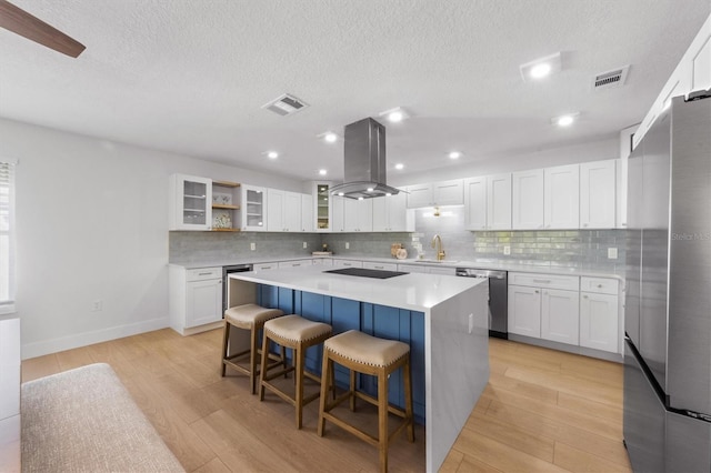 kitchen featuring white cabinetry, island range hood, a kitchen island, and stainless steel appliances