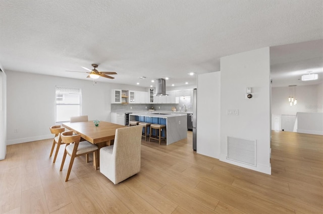 dining room with a textured ceiling, ceiling fan, sink, and light hardwood / wood-style flooring