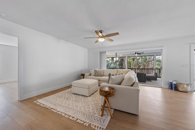 living room with ceiling fan, light hardwood / wood-style floors, and a textured ceiling