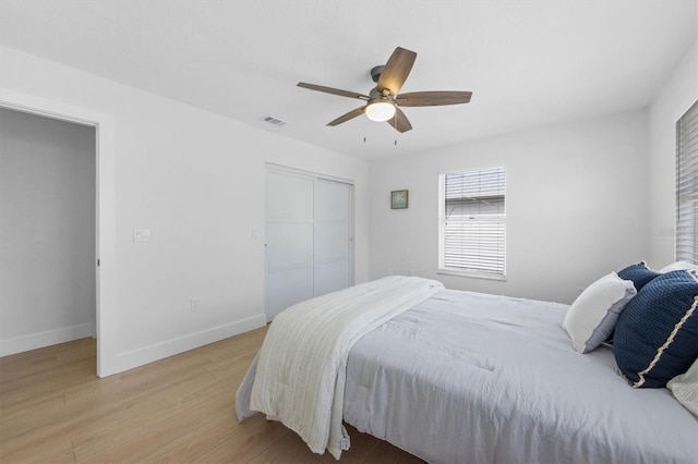 bedroom with ceiling fan, light hardwood / wood-style floors, and a closet