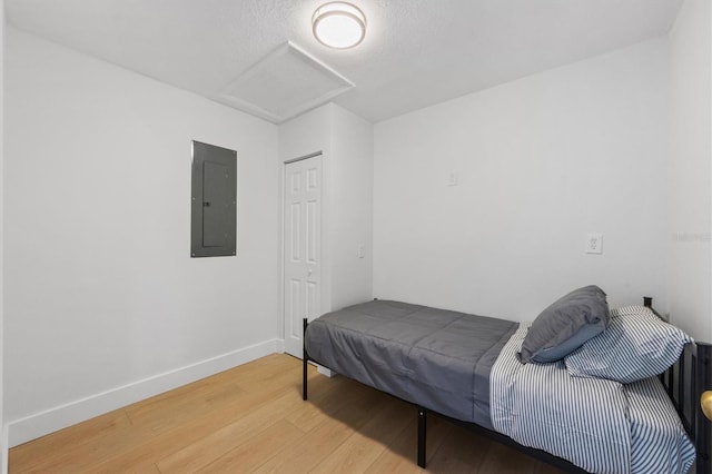 bedroom with hardwood / wood-style flooring, a textured ceiling, and electric panel