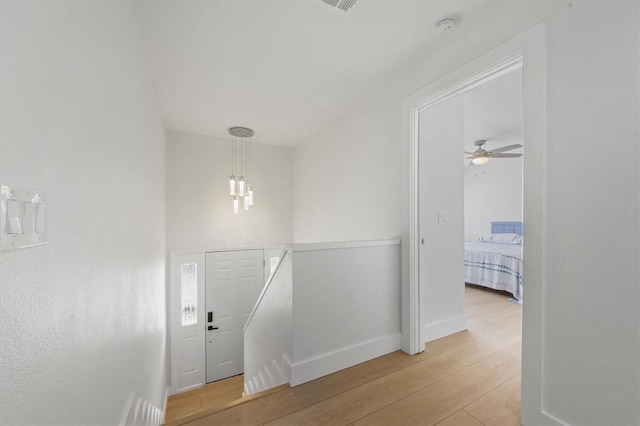 hallway featuring wood-type flooring and an inviting chandelier