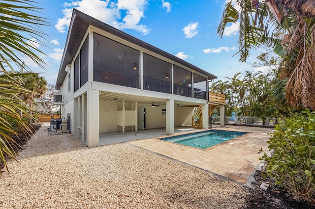 back of property with a fenced in pool, a sunroom, ceiling fan, and a patio