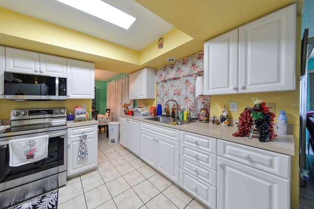 kitchen featuring sink, white cabinets, light tile patterned floors, and appliances with stainless steel finishes