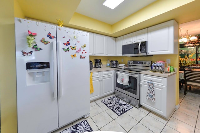 kitchen with white cabinets, an inviting chandelier, light tile patterned floors, and appliances with stainless steel finishes