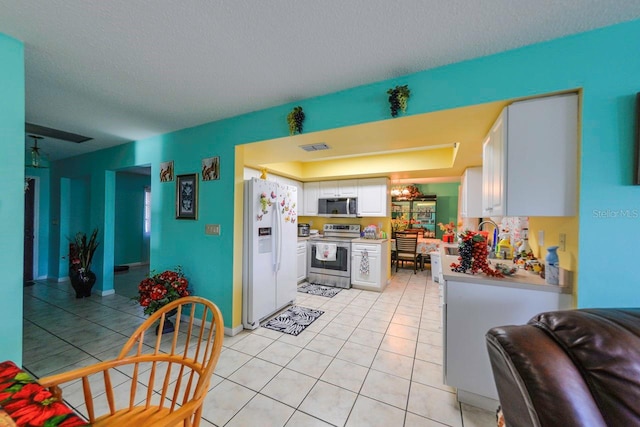 kitchen featuring stainless steel appliances, a textured ceiling, light tile patterned floors, and white cabinetry