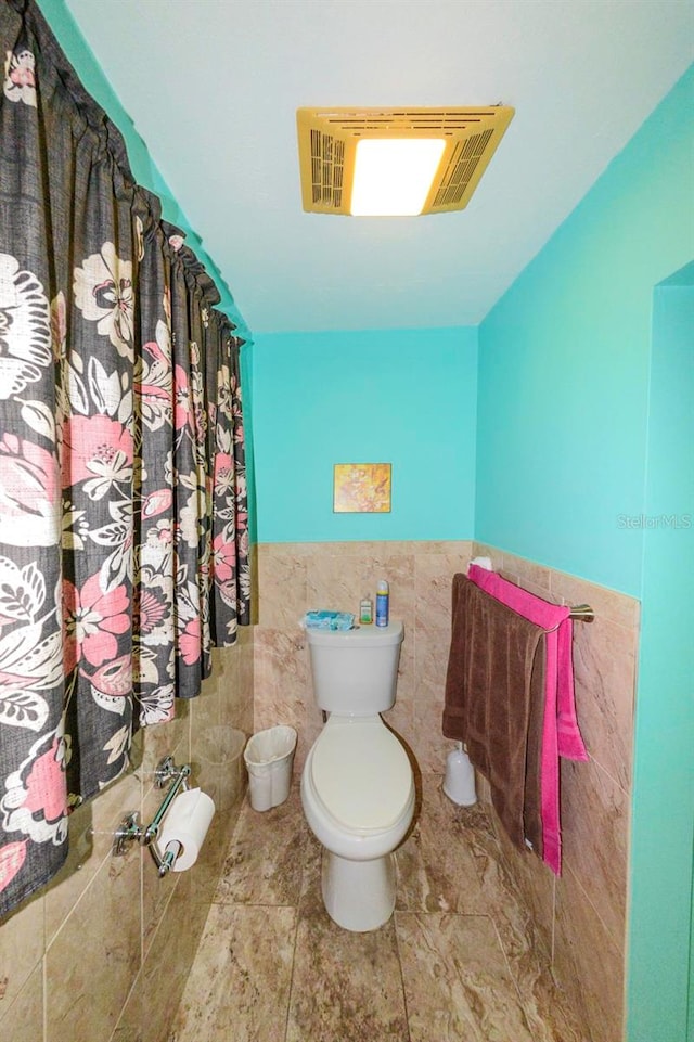 bathroom featuring tile walls and toilet