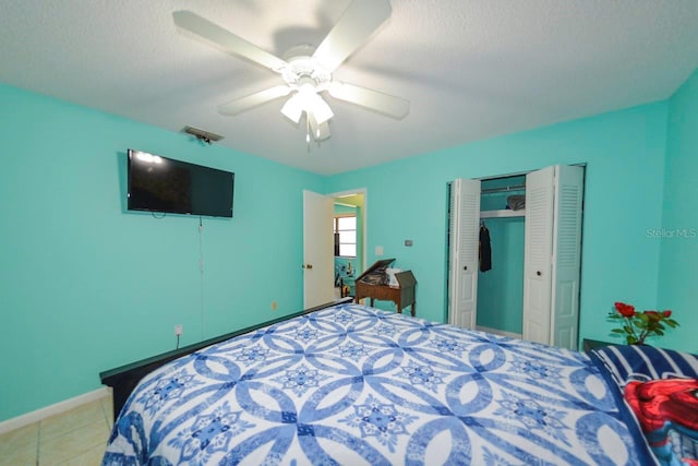 bedroom featuring tile patterned floors, a closet, ceiling fan, and a textured ceiling