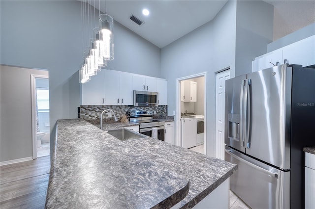 kitchen featuring kitchen peninsula, sink, white cabinetry, appliances with stainless steel finishes, and high vaulted ceiling