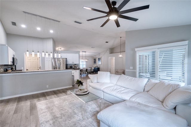 living room with light wood-type flooring, vaulted ceiling, and ceiling fan