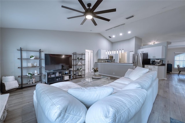 living room featuring ceiling fan, hardwood / wood-style flooring, and vaulted ceiling