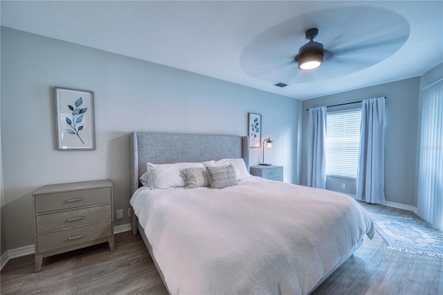 bedroom with ceiling fan, dark wood-type flooring, and a textured ceiling