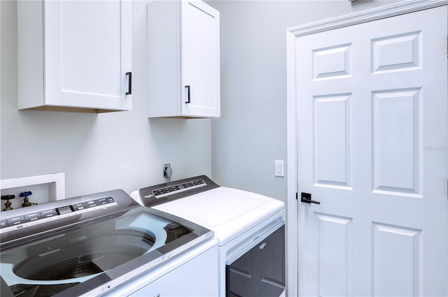 clothes washing area with washing machine and clothes dryer and cabinets