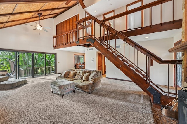 carpeted living room with ceiling fan and high vaulted ceiling