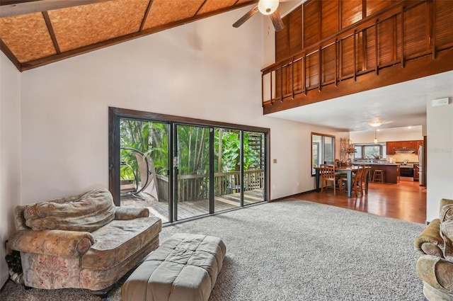 carpeted living room featuring ceiling fan and high vaulted ceiling