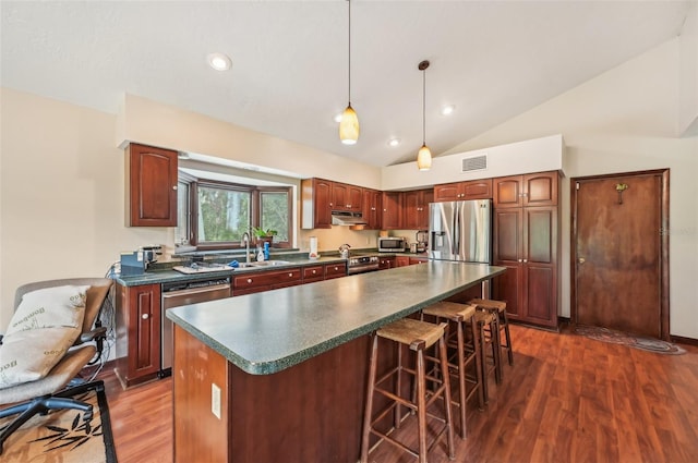 kitchen featuring a center island, dark hardwood / wood-style flooring, stainless steel appliances, hanging light fixtures, and vaulted ceiling