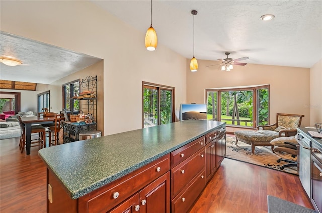 kitchen with ceiling fan, dark hardwood / wood-style flooring, lofted ceiling, and a center island