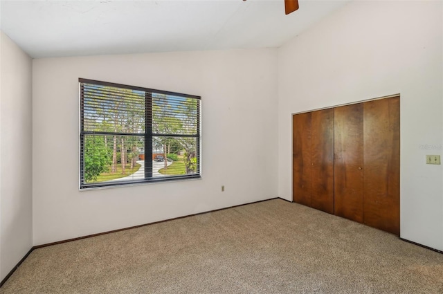 unfurnished bedroom with a closet, carpet flooring, lofted ceiling, and ceiling fan