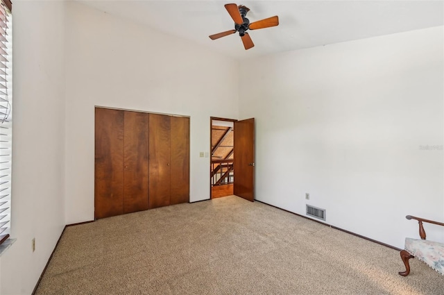 unfurnished bedroom with ceiling fan, light colored carpet, and a closet