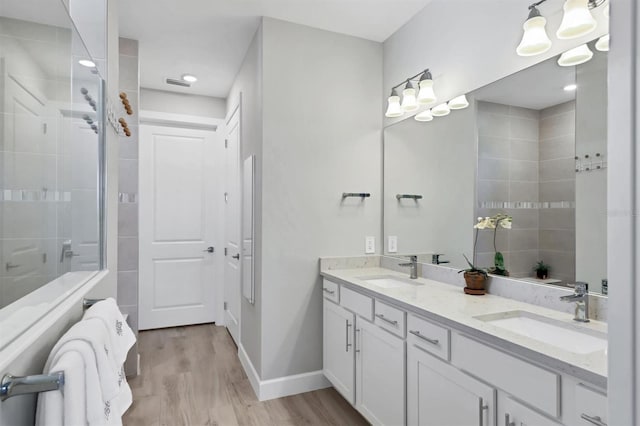 bathroom featuring wood-type flooring, a tile shower, and vanity