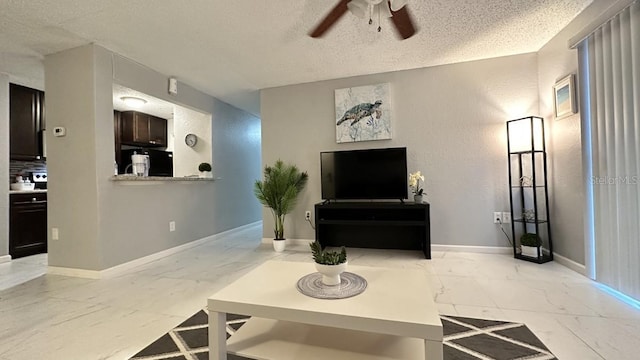 living room featuring ceiling fan and a textured ceiling