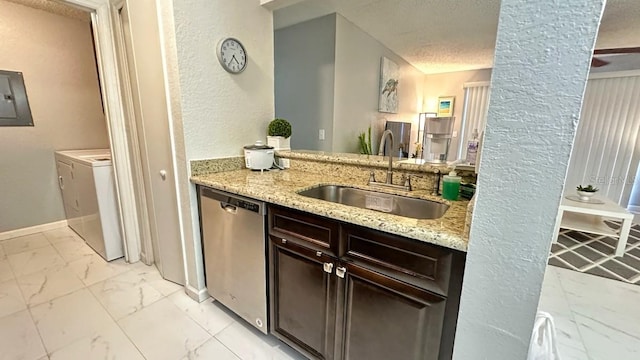 kitchen featuring sink, stainless steel dishwasher, washing machine and dryer, light stone countertops, and dark brown cabinetry