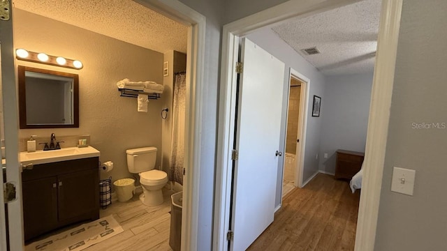 bathroom with hardwood / wood-style floors, vanity, a textured ceiling, and toilet