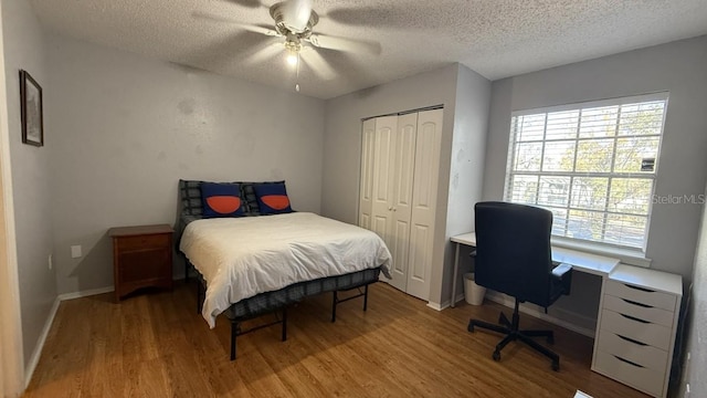 bedroom with ceiling fan, a closet, hardwood / wood-style floors, and a textured ceiling