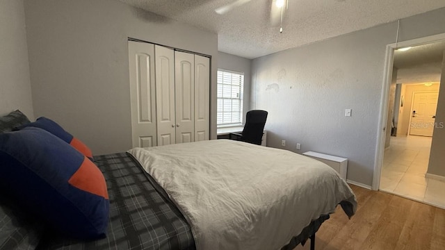 bedroom with wood-type flooring, a textured ceiling, a closet, and ceiling fan