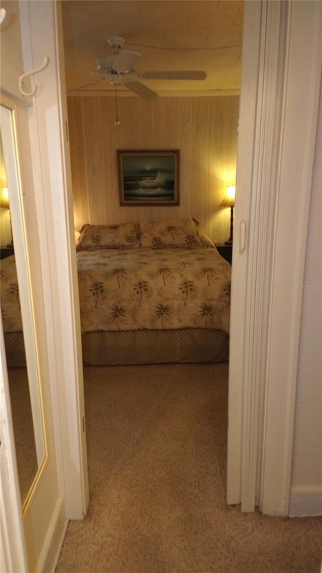 bedroom featuring light colored carpet, ceiling fan, and wood walls